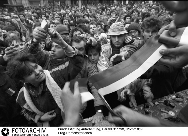Die Demonstranten zerschneiden eine Nationalflagge in schmale Streifen, die sie sich an Revers stecken. Sie wollen zeigen, dass ihre Bewegung patriotisch ist. Und antikommunistisch. Film: 89 1120  Negativ: 10.<BR>Aufnahmedatum: November 1989<BR>Material/Technik: Foto<BR>Aufnahmeort: Prag / Tschechoslowakei (Tschechien)<BR>Signatur: HSchmitt14