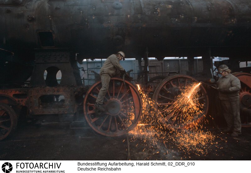 Im Bahnhof Meiningen zerlegen Arbeiter eine 44er Lokomotive. Dia: 33/03<BR>Aufnahmedatum: September 1982<BR>Material/Technik: Foto / Dia<BR>Aufnahmeort: Meiningen / DDR (Deutschland)<BR>Signatur: 02_DDR_010