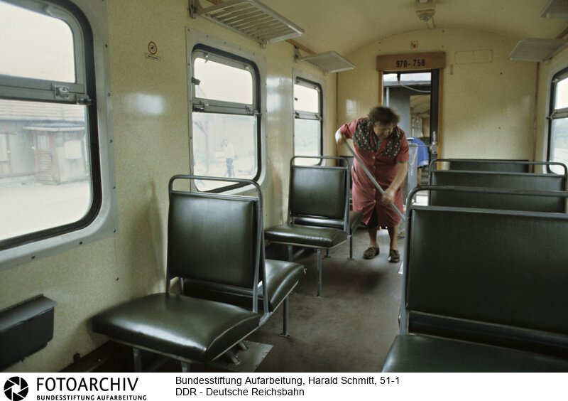 Eine  Putzfrau reinigt den Waggon der Kleinbahn im Bahnhof Putbus.<BR>Aufnahmedatum: September 1982<BR>Material/Technik: Foto<BR>Aufnahmeort: Putbus / Rügen / DDR (Deutschland)<BR>Signatur: 51-1