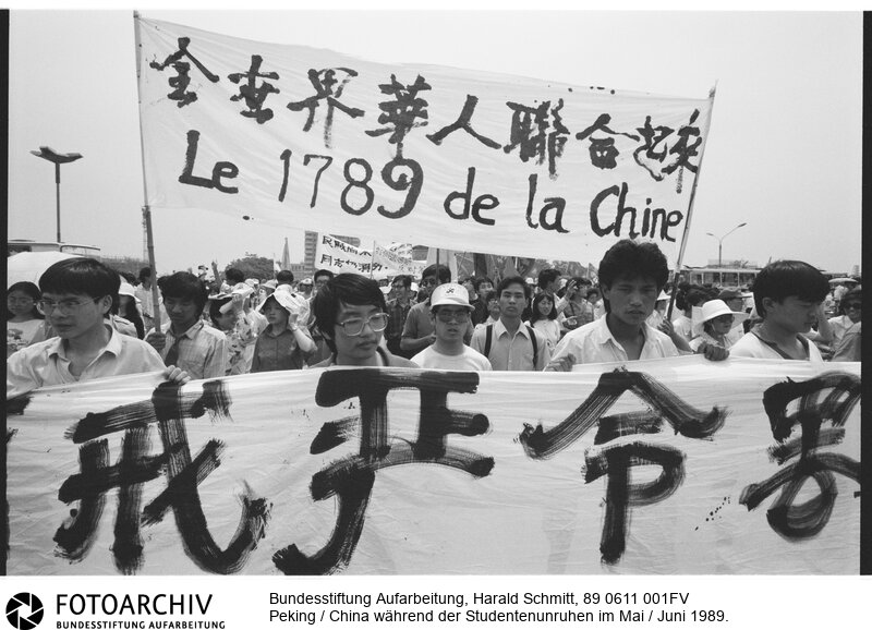 Die Studenten demonstrieren für eine andere Art des Kommunismus. Menschlicher, mehr Freiheiten. Ihr Plakat weist auf die Französische Revolution hin.<BR>Aufnahmedatum: Mai / Juni 1989<BR>Material/Technik: Foto<BR>Aufnahmeort: Peking / China<BR>Signatur: 89 0611 001FV