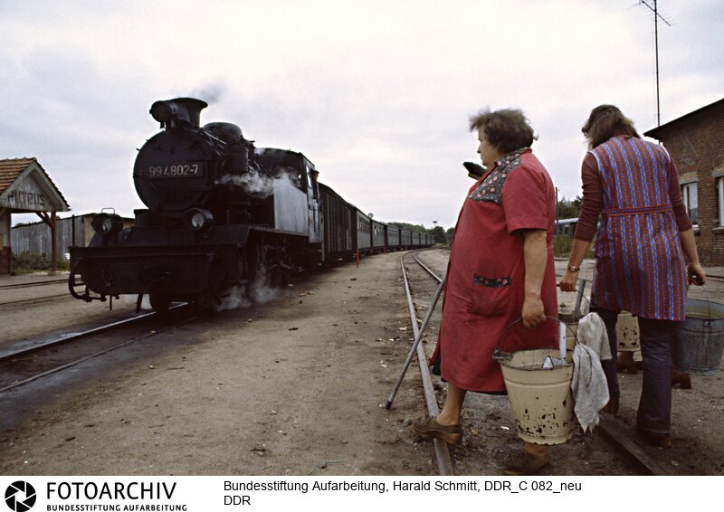 Der "Rasende Roland", eine Schmalspurlokomotive der Deutschen Reichsbahn fährt am 4. September 82 in den Bahnhof von Putbus auf Rügen ein. Die Putzfrauen warten schon.<BR>Aufnahmedatum: 1982<BR>Material/Technik: Foto<BR>Aufnahmeort: Putbus / Rügen / Deutschland<BR>Signatur: DDR_C 082_neu