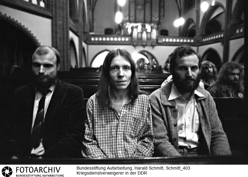 Wolfgang GROSS, (verweigert Reserveübung), Michael FRENZEL (verweigert total) und Heinz GOEBEL (verweigert Reserveübung) drei Kriegsdienstverweigerer die wegen ihres Glaubens nicht zur Waffen greifen wollen und lieber in das Gefängnis gehen. Aufgenommen in einer Kirche in Ost-Berlin. <BR>Aufnahmedatum: 1982<BR>Material/Technik: Foto<BR>Aufnahmeort: Berlin / DDR (Deutschland)<BR>Signatur: Schmitt_403
