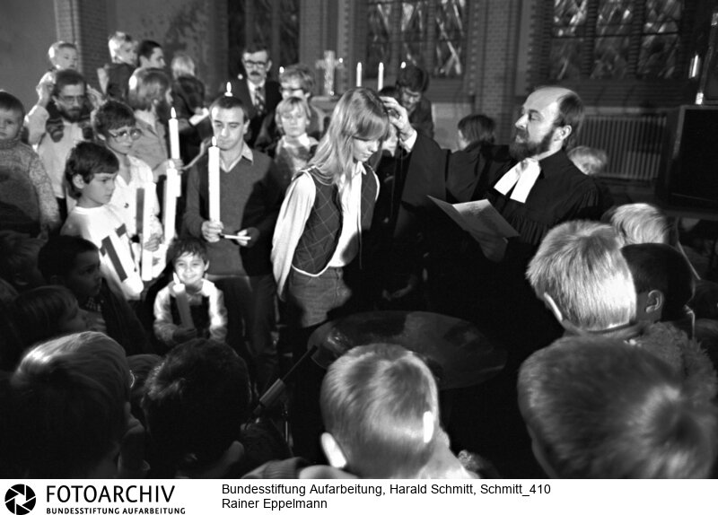 DDR-Friedenspastor Rainer EPPELMANN tauft in seiner Ost-Berliner Samariterkirche alte und junge Gläubige. Film: 82 1108   Negativ: 27<BR>Person: Eppelmann, Rainer, [12.2.1943 -], deutscher evangelischer Pfarrer, Bürgerrechtler und seit 1998 Vorstandsvorsitzender der Bundesstiftung zur Aufarbeitung der SED-Diktatur<BR>Aufnahmedatum: 1982<BR>Material/Technik: Foto<BR>Aufnahmeort: Berlin / DDR (Deutschland)<BR>Signatur: Schmitt_410