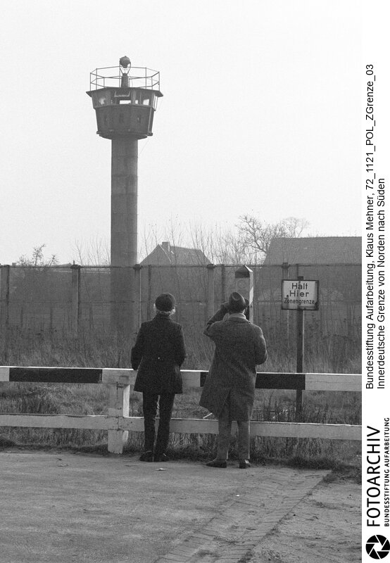 Landkreis Gifhorn (Niedersachsen), 21. 11. 1972. Seit dem Bau der Mauer hat die Deutsche Demokratische Republik (DDR) die Demarkationslinie entlang ihrer Staatsgrenze West optimiert. Die Geländeanpassung der Zonengrenze zementiert die Teilung Deutschlands, für Flüchtlinge besteht Lebensgefahr. Das durch Grenzsoldaten bewachte Sperrsystem ist durch Todesstreifen, Minen und Wachtürme abgeriegelt. Foto: Touristen an der Grenze im geteilten Doppeldorf Zicherie und Böckwitz (DDR). Tourists visit the East-German Border in the divided villages of Zicherie (FRG) and Böckwitz (GDR).<BR>Material/Technik: Foto<BR>Niedersachen<BR>Signatur: 72_1121_POL_ZGrenze_03