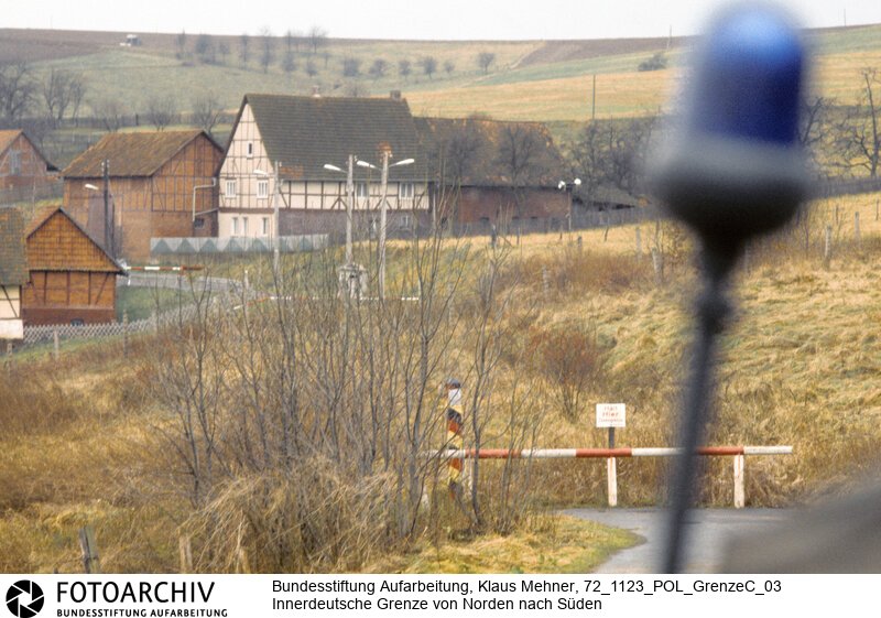 Landkreis Göttingen (Niedersachsen), 23. 11. 1972. Seit dem Bau der Mauer hat die Deutsche Demokratische Republik (DDR) die Demarkationslinie entlang ihrer Staatsgrenze West optimiert. Die dem Gelände angepasste Zonengrenze zementiert die Teilung Deutschlands, für Flüchtlinge besteht Lebensgefahr. Das durch Grenzsoldaten bewachte Sperrsystem ist durch Minen, Todesstreifen und Wachtürme abgeriegelt. Foto: Patrouille des Bundesgrenzschutz (BGS) vor Glasehausen in der DDR. Patrol of West German border guard in front of Glasehausen.<BR>Material/Technik: Foto<BR>Niedersachen<BR>Signatur: 72_1123_POL_GrenzeC_03
