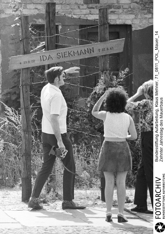 Foto: Touristen an der Gedenkstätte für die auf der Flucht zu Tode gekommenen Rentnerin. Berlin (Berlin West), 11. 08. 1971. Berliner Mauer ? Wall of Shame. Vorschau zum zehnten (10.) Jahrestag des Mauerbaus. The wall in the districts Kreuzberg and Wedding.<BR>Material/Technik: Foto<BR>Berlin (West)<BR>Signatur: 71_0811_POL_Mauer_14