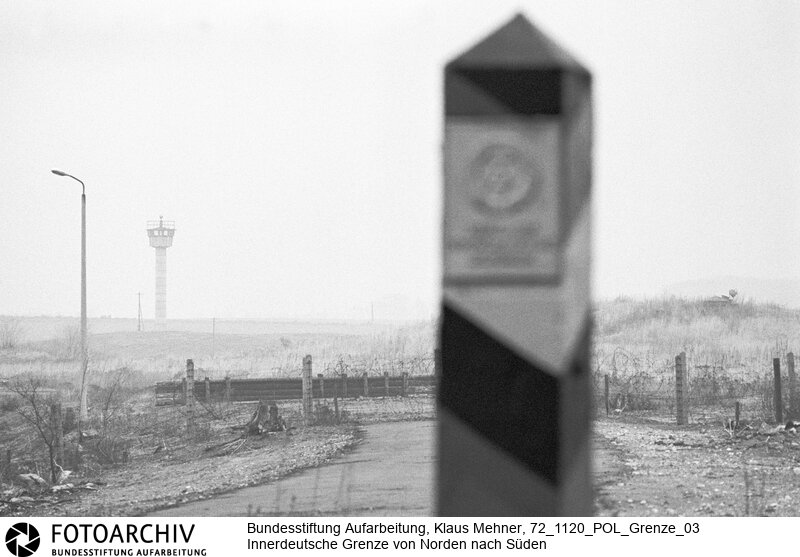 Landkreis Lauenburg (Schleswig-Holstein), 20. 11. 1972. Seit dem Bau der Mauer hat die Deutsche Demokratische Republik (DDR) die Demarkationslinie entlang ihrer Staatsgrenze West optimiert. Die Geländeanpassung der Zonengrenze zementiert die Teilung Deutschlands, für Flüchtlinge besteht Lebensgefahr. Das durch Grenzsoldaten bewachte Sperrsystem ist durch Todesstreifen, Minen und Wachtürme abgeriegelt. Foto: Grenzzeichen der DDR bei Wietingsbek (Ratzeburg) mit Wachtturm und Bunker. East-German Border near Wietingsbek (Ratzeburg) with watchtower and shelter.<BR>Material/Technik: Foto<BR>Schleswig-Holstein<BR>Signatur: 72_1120_POL_Grenze_03