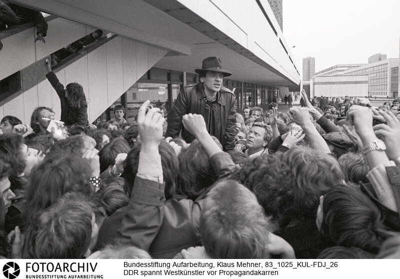 Westkünstler vor Propagandakarren gespannt. Berlin (Bezirk Berlin) DDR, 25. 10. 1983. Udo Lindenberg, Fans ohne Eintrittskarten vor dem Palast der Republik. Die Kampagne der DDR gegen die Nachrüstung läuft auf Hochtouren. Die Freie Deutsche Jugend (FDJ), Nachwuchsorganisation der SED, organisierte im Palast der Republik ein Konzert unter dem Motto: Künstler für den Frieden. Die Veranstaltung unter Beteiligung von Rockstars aus dem Westen fand vor handverlesenem Publikum statt.<BR>Material/Technik: Foto<BR>Bezirk Berlin<BR>Signatur: 83_1025_KUL-FDJ_26