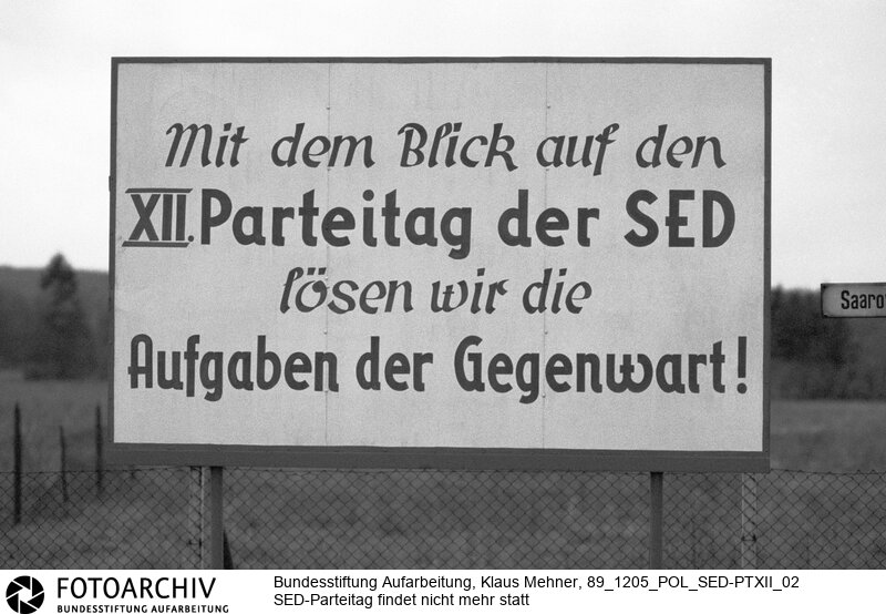 Botschaft einer vergangenen Epoche. Fürstenwalde (Bezirk Frankfurt Oder) DDR, 05. 12. 1989. Foto: Agitation der SED an der Landstrasse nach Bad Saarow. Der für Mai 1990 angekündigte zwölfte Parteitag der SED (Sozialistische Einheitspartei Deutschland) ist durch die friedliche Revolution in der DDR obsolet geworden. Höhepunkt des Parteitages sollte die Planerfüllung des in Wahrheit gescheiterten Wohnungsbauprogramms sein.<BR>Material/Technik: Foto<BR>Bezirk Frankfurt Oder<BR>Signatur: 89_1205_POL_SED-PTXII_02