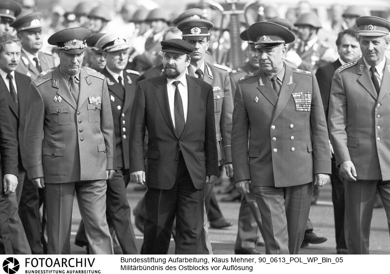 Berlin (Bezirk Berlin) DDR, 13. 06. 1990. Warschauer Pakt vor Auflösung. Während einer dreitägigen Tagung in der Deutschen Demokratischen Republik (DDR) beraten die Minister für Verteidigung die Abwicklung des Bündnisses. Die Konferenz der Warschauer Vertragsstaaten findet im Tagungszentrum der Nationalen Volksarmee (NVA) in Strausberg statt. Kranzniederlegung am Mahnmal Unter den Linden mit kleinem militärischem Zeremoniell. Foto (v.l.n.r.): Minister Jordan Mutaftschiev (Bulgarien), Rainer Eppelmann (DDR), Marschall Dimitri Jasow (UdSSR), Miroslav Vacek (CSSR) im Anmarsch.<BR>Material/Technik: Foto<BR>Bezirk Berlin<BR>Signatur: 90_0613_POL_WP_Bln_05