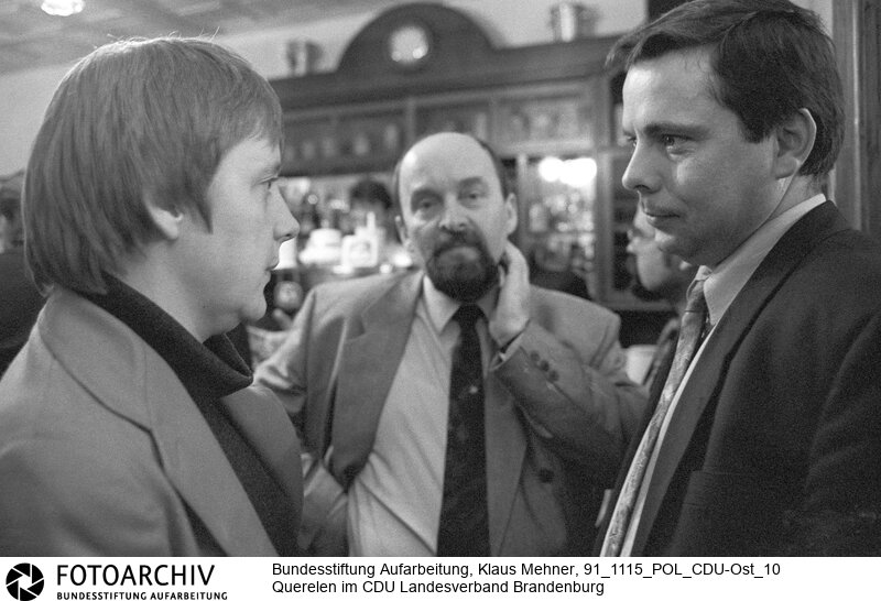 Querelen im CDU Landesverband. Borkheide (Brandenburg), 15. 11. 1991. Foto: Angela Merkel (37), Rainer Eppelmann (48) bei Kungelei. Im Auftrag des Bundeskanzlers soll die Bundesfrauenministerin einen linken Parteivorsitzenden des CDU-Landesverbandes Brandenburg verhindern. Der Schaulauf der Kandidaten findet unter den Augen der Ministerin im Fliegerheim statt.<BR>Material/Technik: Foto<BR>Brandenburg<BR>Signatur: 91_1115_POL_CDU-Ost_10