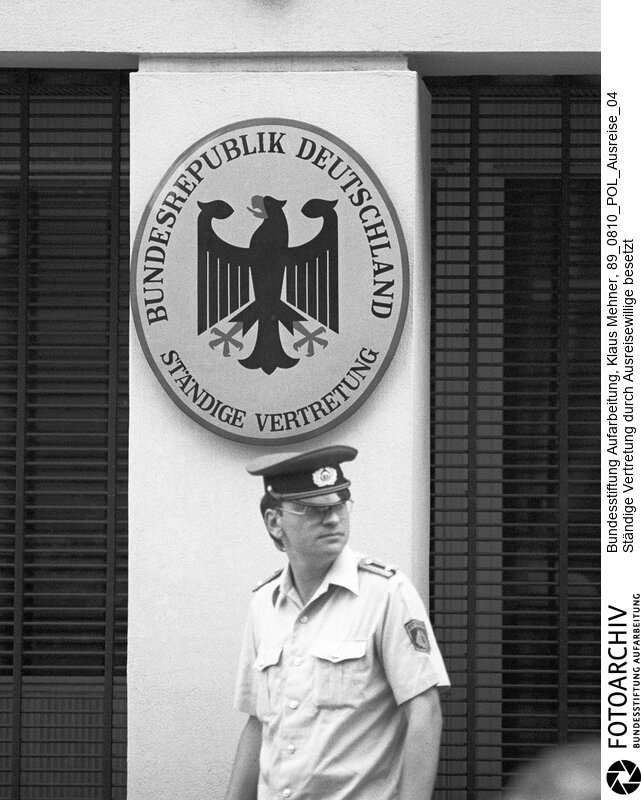 Ständige Vertretung durch Ausreiser besetzt. Berlin (Bezirk Berlin) DDR, 10. 08. 1989. Foto: Posten der Volkspolizei vor dem Haupteingang der StäV. 113 Ausreisewillige haben die Schließung der Ständigen Vertretung (StäV) der Bundesrepublik in der Hauptstadt der Deutschen Demokratischen Republik (DDR) erzwungen. Trotz rigoroser Kontrollen durch die Volkspolizei (Vopo; VP) gelangten immer wieder Flüchtlinge, die mit dieser Aktion die Ausreise erzwingen wollen auf das exterritoriale Gelände der diplomatischen Residenz in Ost-Berlin.<BR>Material/Technik: Foto<BR>Bezirk Berlin<BR>Signatur: 89_0810_POL_Ausreise_04