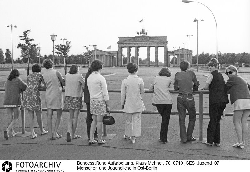 Menschen und Jugendliche in Ost-Berlin. Berlin (Bezirk Berlin) DDR, 10. 07. 1970. Foto: Besucher bei Besichtigung der Mauer am Brandenburger Tor. An der Grenze, dem abgeriegelten Brandenburger Tor, werfen Einheimische und Besucher aus der Provinz einen Blick über die Mauer nach West-Berlin.<BR>Material/Technik: Foto<BR>Bezirk Berlin<BR>Signatur: 70_0710_GES_Jugend_07