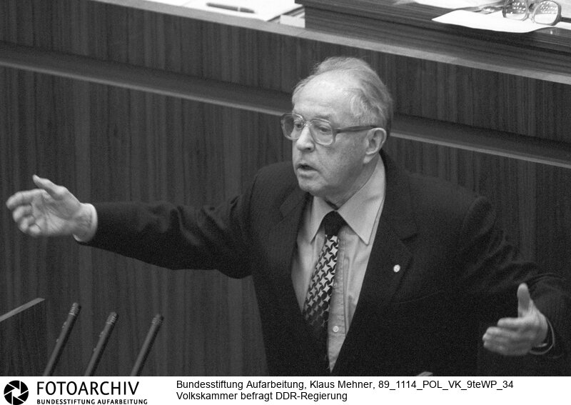 Revolution erreicht Volkskammer, Abgeordnete fragen. Berlin (Bezirk Berlin) DDR, 13. 11. 1989. Foto: Erich Mielke (SED), Minister fuer Staatssicherheit bei Rede. Volkskammerabgeordnete befragen Ex-Minister. Sichtlich unbeholfen agierten Mitglieder der DDR-Regierung auf ungewohnte Fragen von Parlamentariern der Volkskammer. Fuer Heiterkeit sorgte der Staatsicherheitsminister (MfS, Stasi) mit dem Satz: Ich liebe, ich liebe doch alle, alle Menschen! Na ich liebe doch!<BR>Material/Technik: Foto<BR>Bezirk Berlin<BR>Signatur: 89_1114_POL_VK_9teWP_34