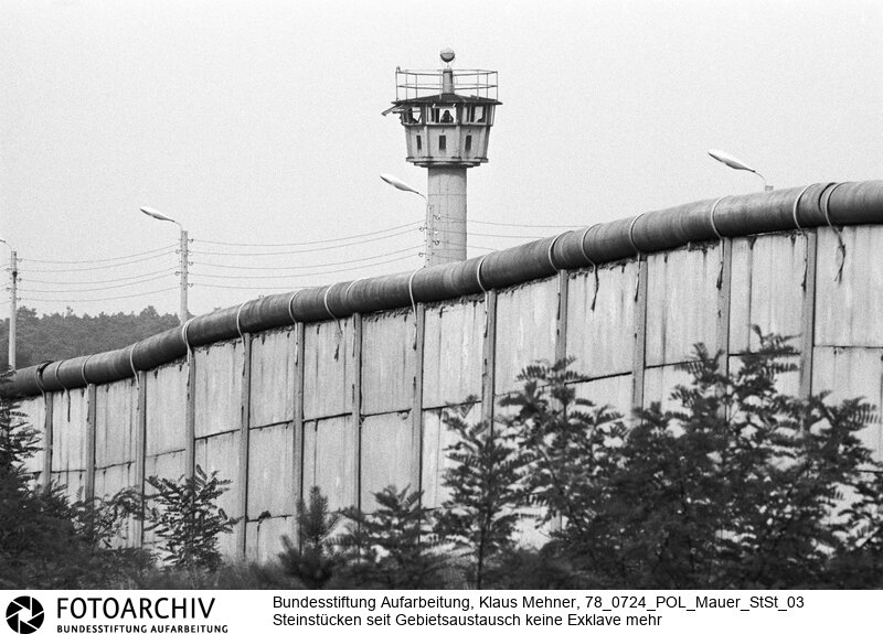 Berlin (Berlin West), 24. 07. 1978. Viermächteabkommen macht Exklave zugänglich. Mit dem Gebietsaustausch zwischen dem Berliner Senat und der DDR unter dem Dach des Abkommens ist Steinstücken seit 1972 keine Exklave mehr. Die Grenzziehung an der Brücke über die Gleise der DDR-Reichsbahn wurde durch einen kuriosen Kompromiss gelöst: Die Brücke selbst und der darüber befindliche Luftraum kamen zu West-Berlin. Der Erdboden und Luftraum unter der Querung verblieb bei der DDR. Foto: Mauer am Korridor nach Steinstücken.<BR>Material/Technik: Foto<BR>Berlin West<BR>Signatur: 78_0724_POL_Mauer_StSt_03